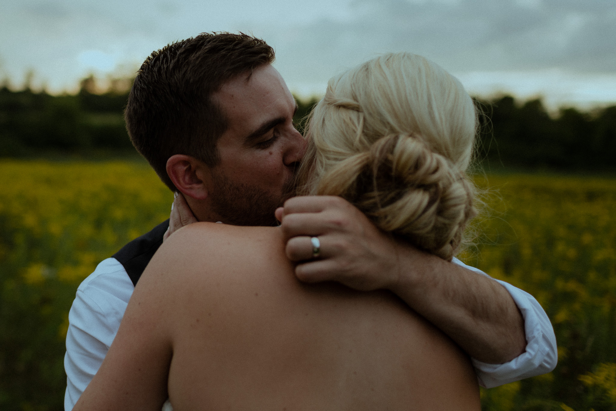 groom embracing his wife during sunset portrait session