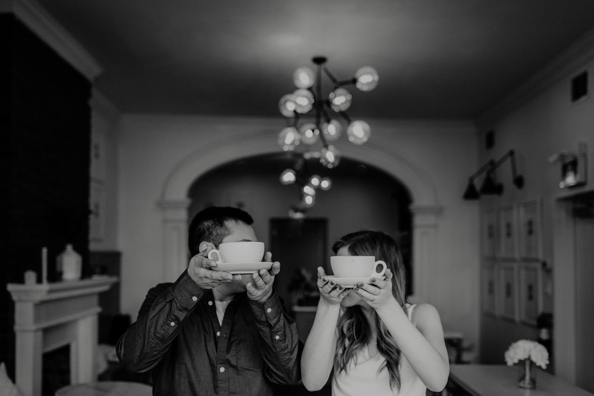 indie couple covering their faces with coffee cups