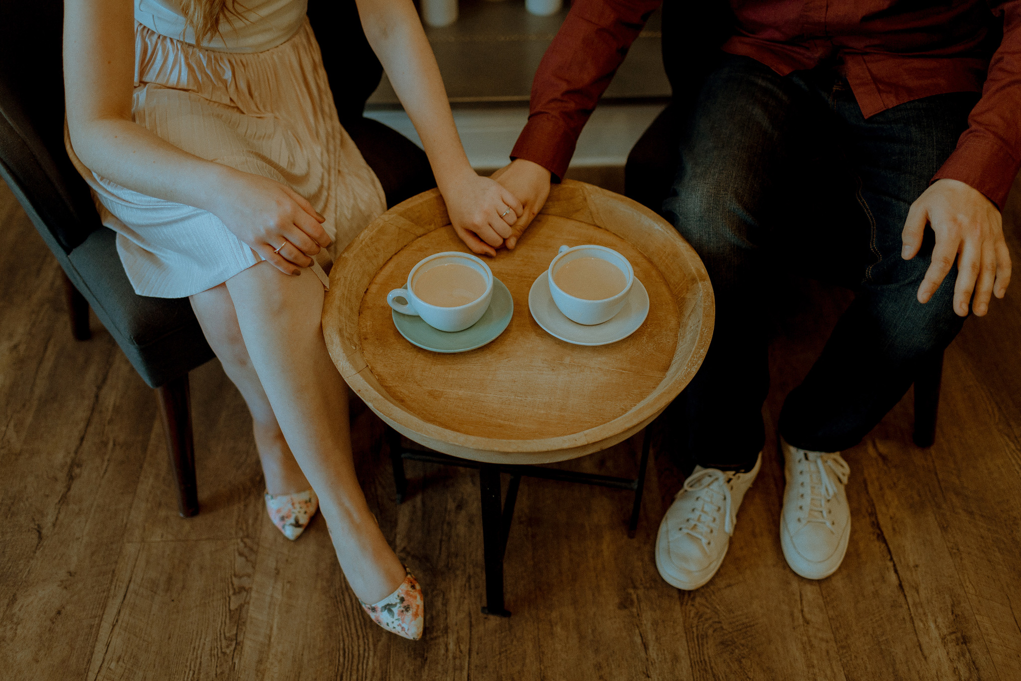 vintage couple holding hands on table with two cups of coffee at the best cafe in Hamilton