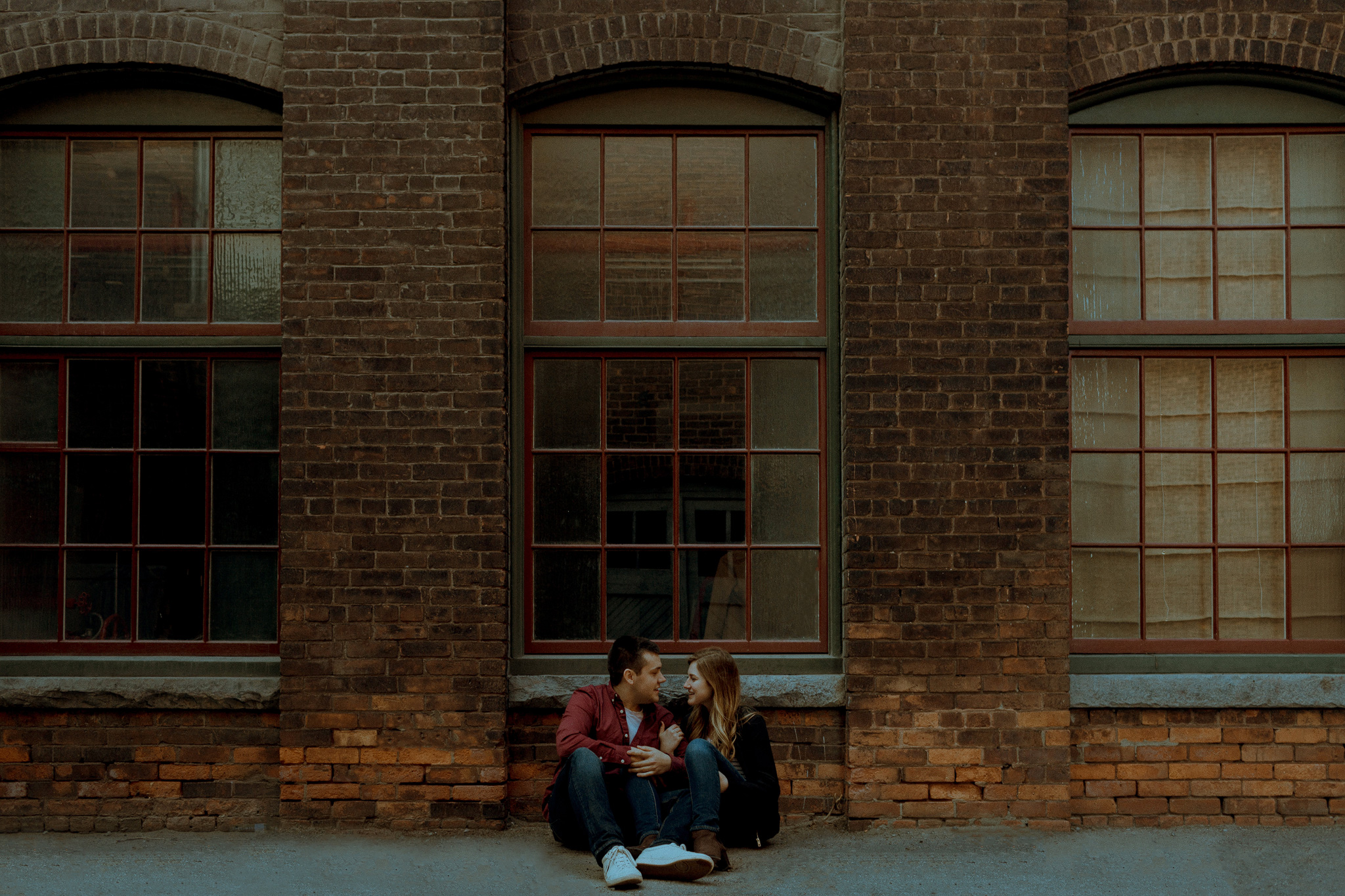 industrial engagement photo of couple sitting below window