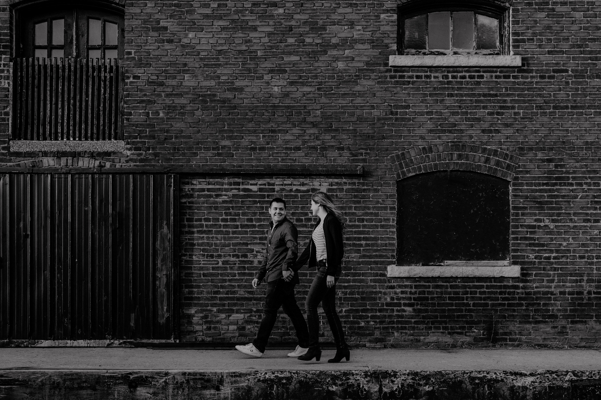 In love couple walking by brick wall
