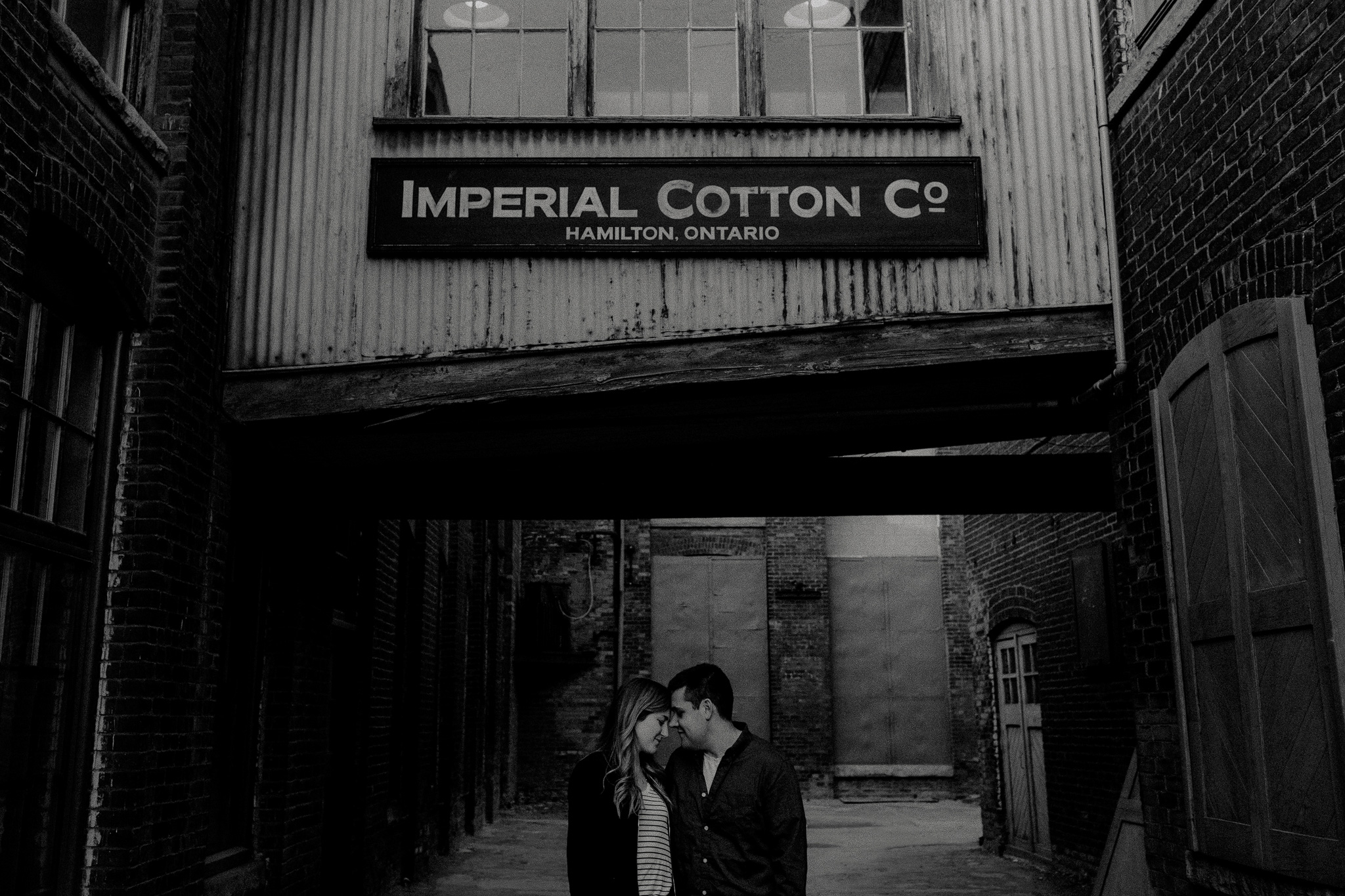 Engagement photo in front of Imperial Cotton Co. sign at The Cotton Factory