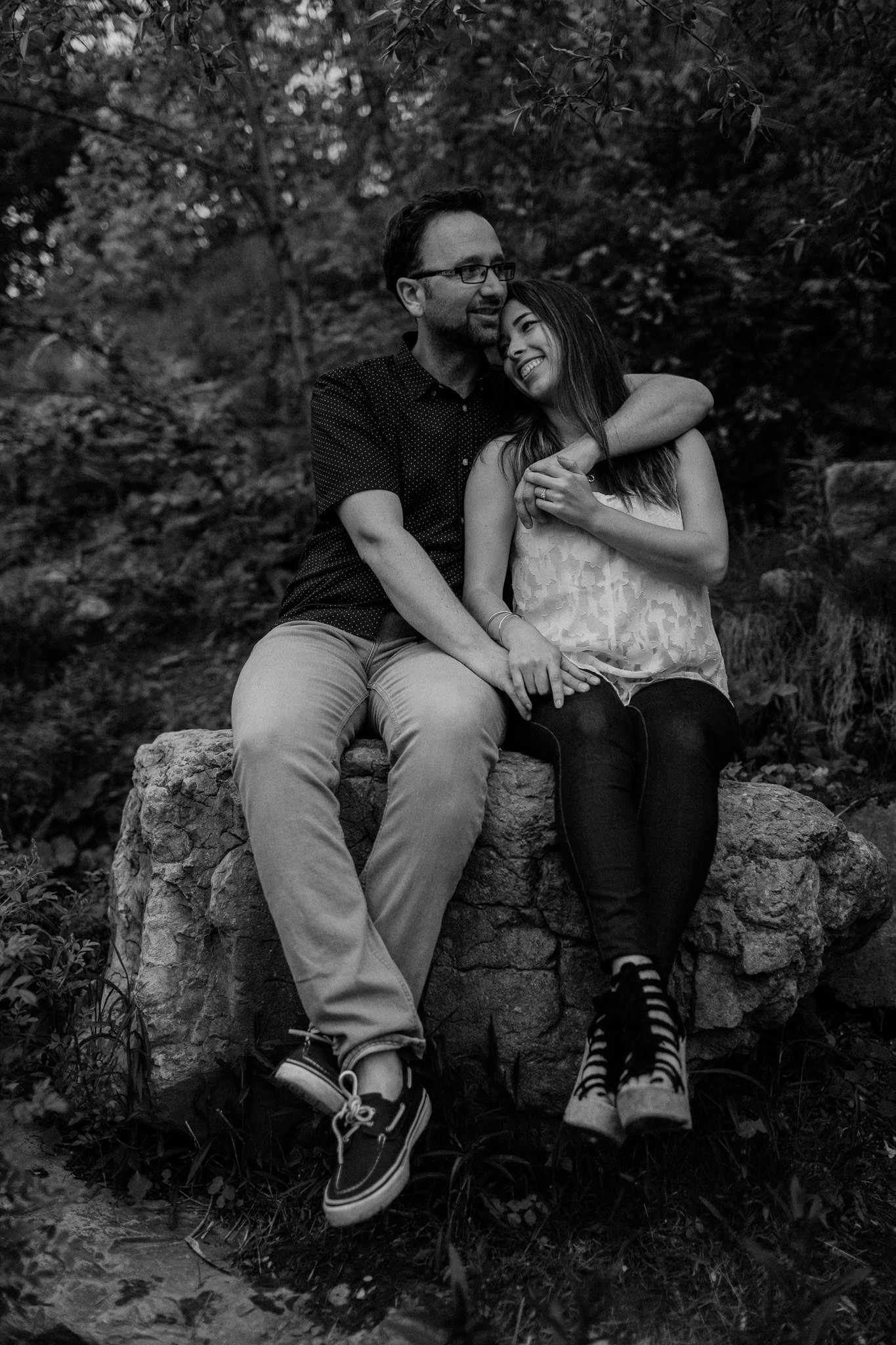Couple being in love, sitting on a rock in the woods