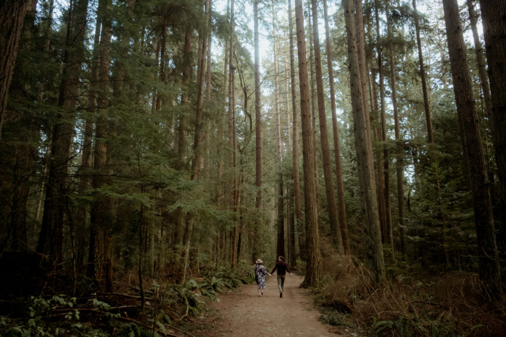 Couple running through the forest of Pacific Spirit Regional Park