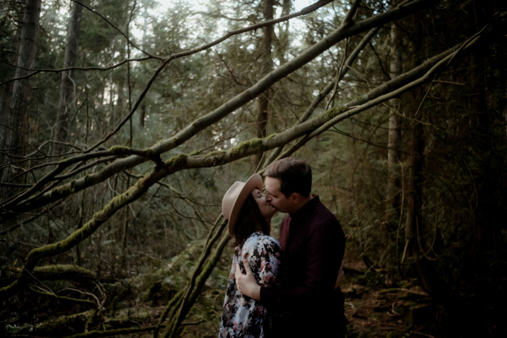Couple kissing under branches at Pacific Spirit Regional Park
