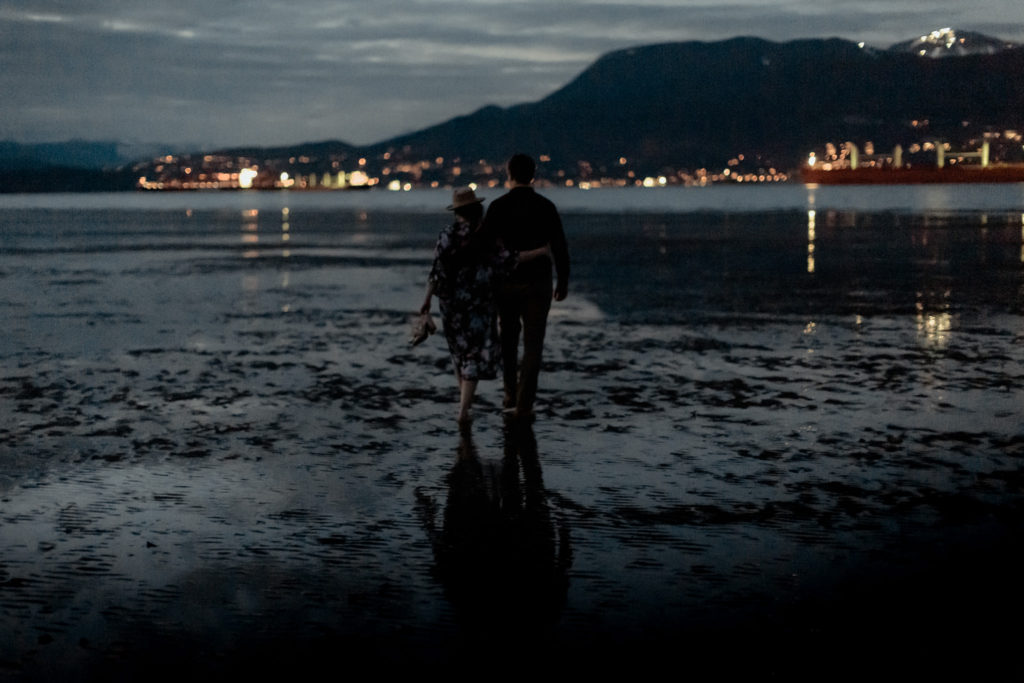 Couple walking barefoot at Jericho Beach in the evening